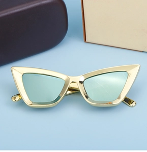 Dettaglio occhiali da sole cat-eye dorati con lenti verde acqua e custodia di lusso
