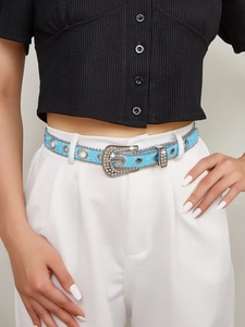 Close-up of sparkling blue sequin belt with silver rhinestones and chain on white pants