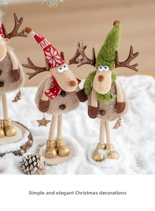 Statuine di renne natalizie in peluche con cappelli di maglia e stivali dorati sulla neve