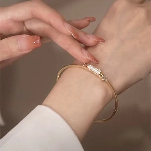 Elegant gold-tone bangle with sparkling micro-paved zircon slider on a sleek metal ring