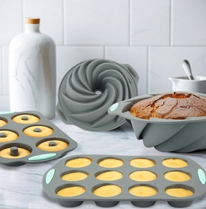 Set of grey silicone baking molds with green handles on a bright marble surface