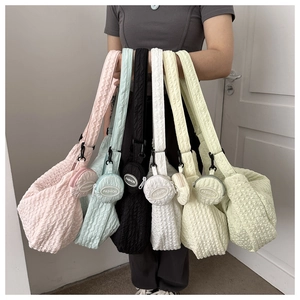 Detail of colorful pleated crossbody bags showing soft fabric texture and mini coin pouches