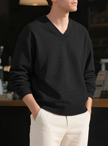 Detailed view of black V-neck knitted sweater with textured diamond pattern