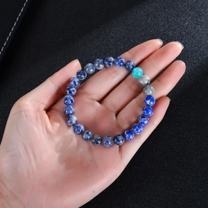 Detailed view of solar system natural stone beads held in hand with deep blue textures