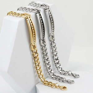 Men's 18K gold and silver stainless steel Cuban link bracelet on white display blocks