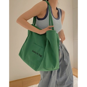 Detail of green canvas tote bag with black text and adjustable shoulder strap