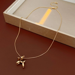 Detail view of a gold-plated balloon dog pendant necklace resting on a jewelry box
