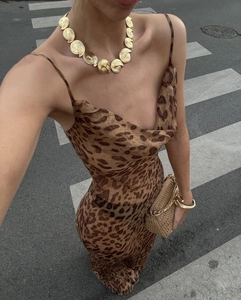 Détail d'une robe maxi léopard avec collier doré texturé et pochette élégante