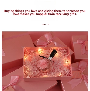 Close-up of pink gift box with silk ribbon, LED fairy lights, and decorative perfume bottle
