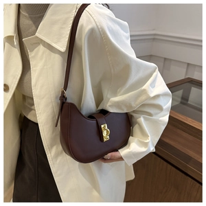 Vue détaillée d'un sac demi-lune marron foncé rétro avec boucle dorée sur un mannequin