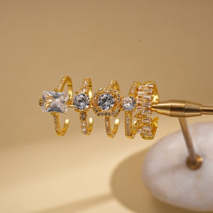 Detailed close-up of four gold-plated rings with cubic zirconia on a jewelry display stand