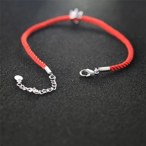 Detail view of red braided cord bracelet featuring silver lobster clasp and adjustable chain