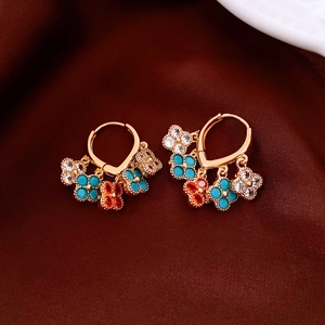 Detail view of 18K gold plated flower fringe earrings on dark brown silk background