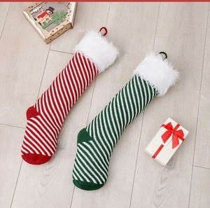 Festive striped knit Christmas stockings with plush cuffs on light wooden floor decor
