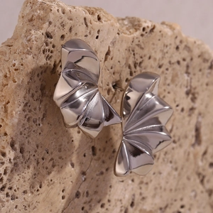 Macro detail of silver geometric petal earrings on natural stone showing metallic texture