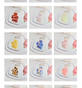 Detail showing various patterned acetate hair claw clips on a white texture background
