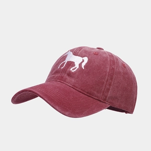 Close-up of embroidery of white horse silhouette on a burgundy washed cotton baseball cap