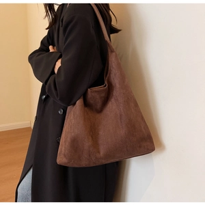 Close-up of brown suede tote bag featuring a wide shoulder strap and spacious interior