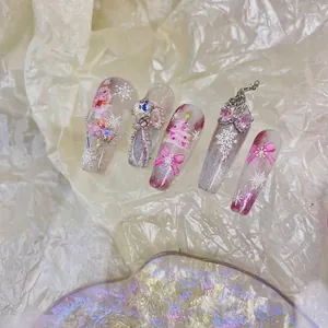 Pink Christmas press-on nails with snowflake art, 3D bows, and gems in a dreamlike set