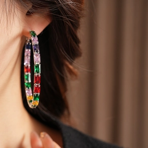 Close-up of rainbow zirconia hoop earrings worn on model featuring colorful step-cut stones