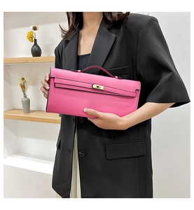 Close-up of vibrant magenta handbag with golden twist lock held by a professional model