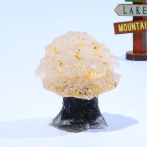 Detailed view of handmade crystal tree with clear stones and golden foil on a dark base