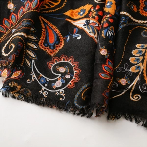 Detailed close-up of retro black paisley scarf featuring vibrant orange and red fringe edges