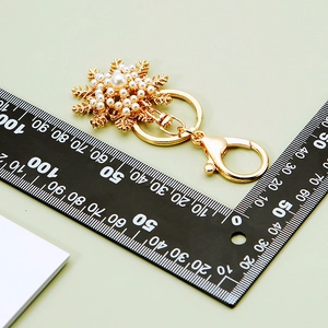 Macro detail of golden snowflake keychain with pearls and lobster clasp measuring 10cm