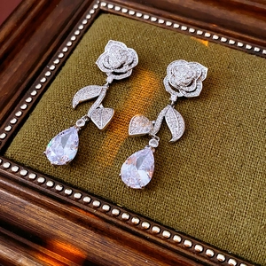 Detailansicht silberne Rosen-Ohrstecker mit Wassertropfen-Zirkon-Anhängern auf Samt