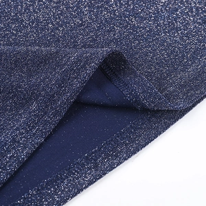 Macro detail of navy blue knit fabric with silver glitter threads and precise stitching