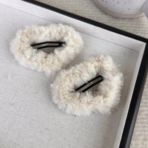 Close-up of fuzzy cream heart hair clips on a white fabric tray for a cozy look