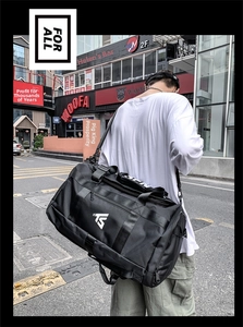 Detail of a large black oxford fabric travel backpack with wide shoulder straps on a model