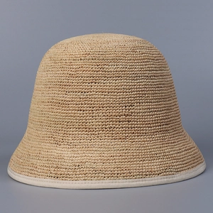 Close-up of fine woven texture and white minimalist trim on a beige raffia bucket hat