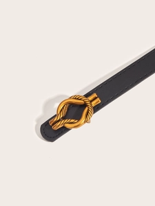 Detailed macro shot of a black PU leather belt with a golden twisted metal buckle
