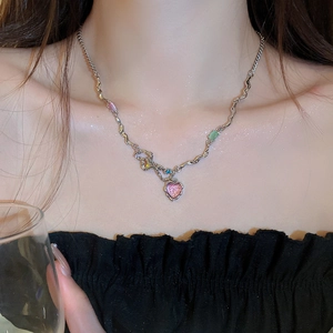 Détail d'une chaîne ondulée avec pendentif cœur rose et pierres colorées sur le cou