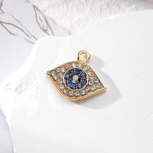 Detailed view of evil eye charm pendant with blue and white zircons on white marble