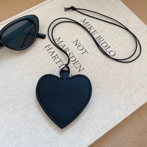 Detail of a black leather heart-shaped pendant with lychee texture on a vintage book
