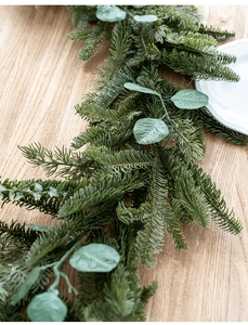 Close-up of realistic pine needle and eucalyptus leaf garland on a rustic wood surface