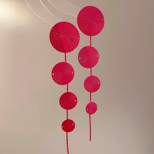Detailed view of pink woven circular drop earrings with textured disc fringe patterns