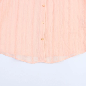 Detail of pink striped shirt hem with elegant gold buttons and soft fabric texture
