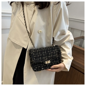 Detailed view of black tweed texture with gold threads and light gold twist lock closure