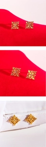 Detailed view of gold flower cluster earrings with sparkling zircon accents on red background