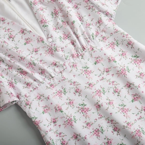 Dettaglio di abito a fiori con scollo a V, bottoni bianchi e trama del tessuto in chiffon