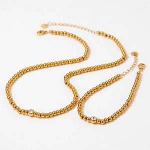 Detailed view of gold beaded necklace and bracelet set with sparkling zircon stones