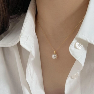Elegant 925 silver necklace featuring a round white pearl on a gold chain worn by a model