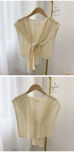 Detail of cream knitted shawl with arrow openwork pattern and knotted closure design