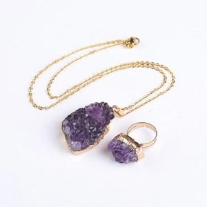 Detailed view of raw purple amethyst pendant and ring set on gold plated metal base