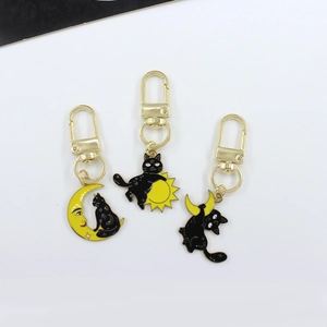 Three punk style black cat keychains with yellow moon and sun charms in gold metal finish