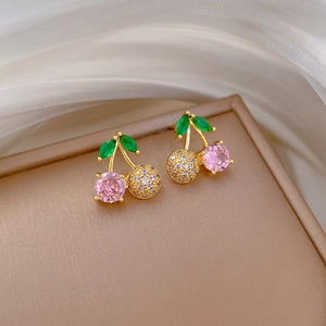 Close-up of gold cherry stud earrings with pink gemstone and clear micro-pave crystals