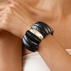 Detailed view of bold elastic bracelet with alternating black and gold geometric modules